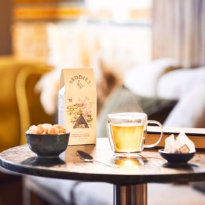 Teetasse, Teepackung, Zuckerschale, Buch und Teebeutel auf Tisch