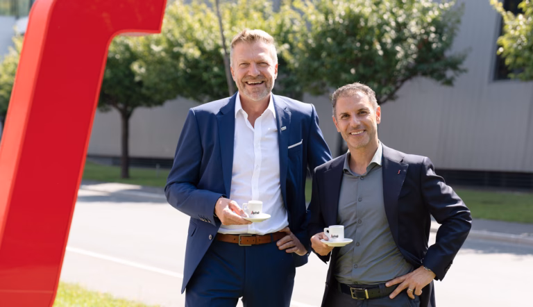 Zwei Männer im Anzug mit Espressotassen